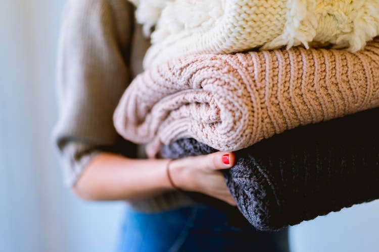 autumn photo ideas for instagram - a girl with folded sweaters in her hands